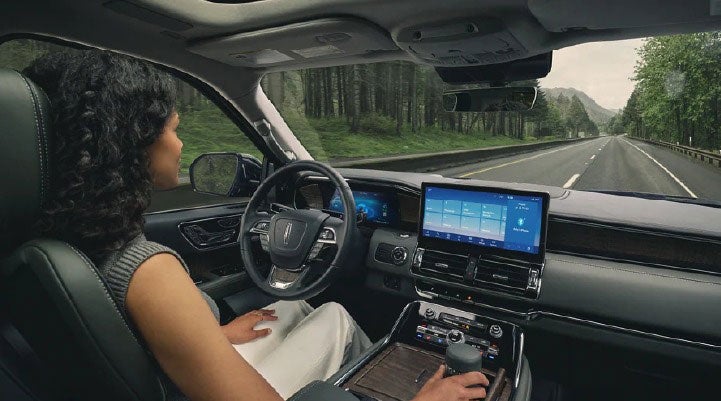 A driver of a Lincoln Navigator SUV is shown utilizing the ActiveGlide feature.