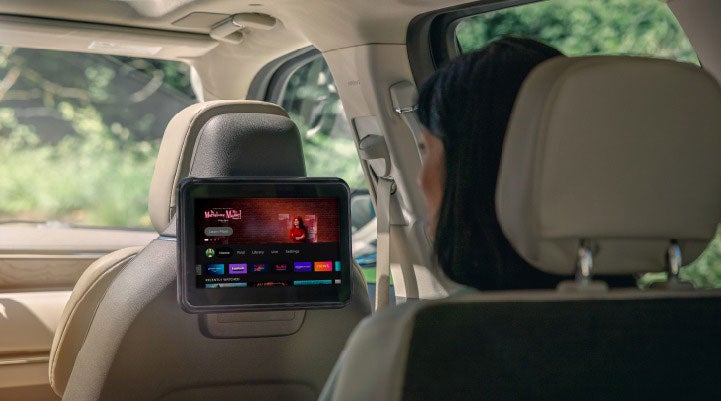 A woman is seated in the second row of a Lincoln Navigator® SUV viewing the Lincoln Play with Amazon Fire TV screen.