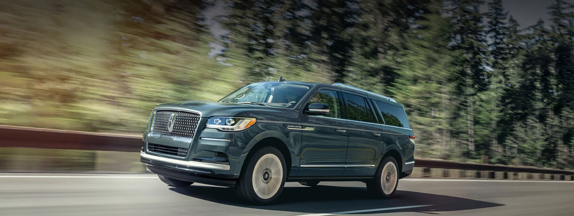 A Lincoln Navigator SUV is being driven on a tree-lined road