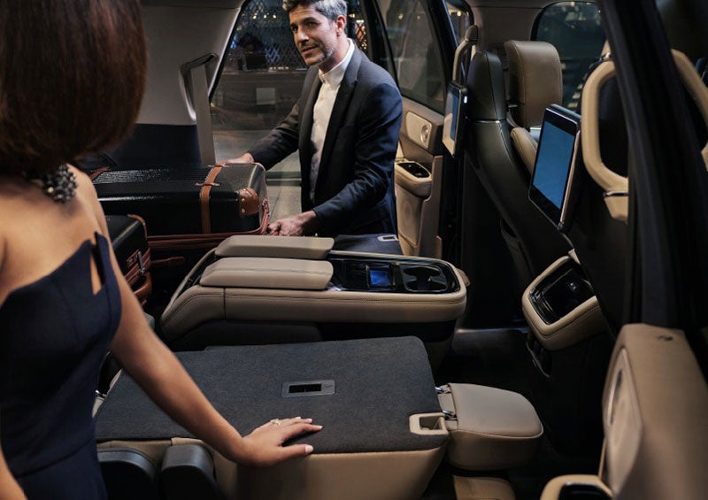 A man is pulling a suitcase out of the folded-flat second row of a 2023 Lincoln Navigator SUV. | Haldeman Lincoln in Allentown PA