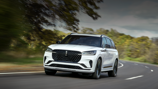 A white 2025 Lincoln Aviator® SUV is being driven down a road lined with trees. | Haldeman Lincoln in Allentown PA