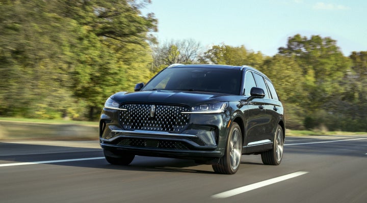 A 2026 Lincoln Black Label™ Aviator® SUV is being driven down a road lined with trees. | Haldeman Lincoln in Allentown PA