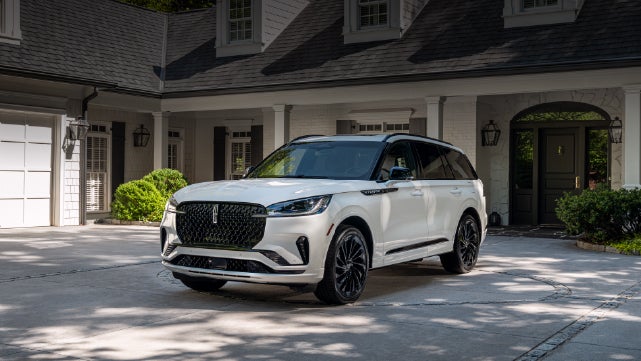 A white 2026 Lincoln Aviator® SUV is parked in the driveway of a luxury home. | Haldeman Lincoln in Allentown PA